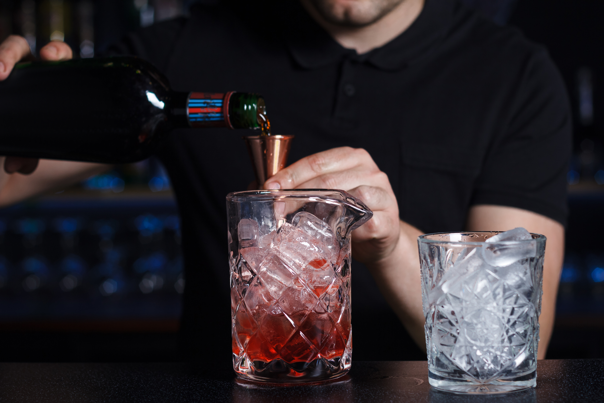bartender pouring shot into fully iced glass