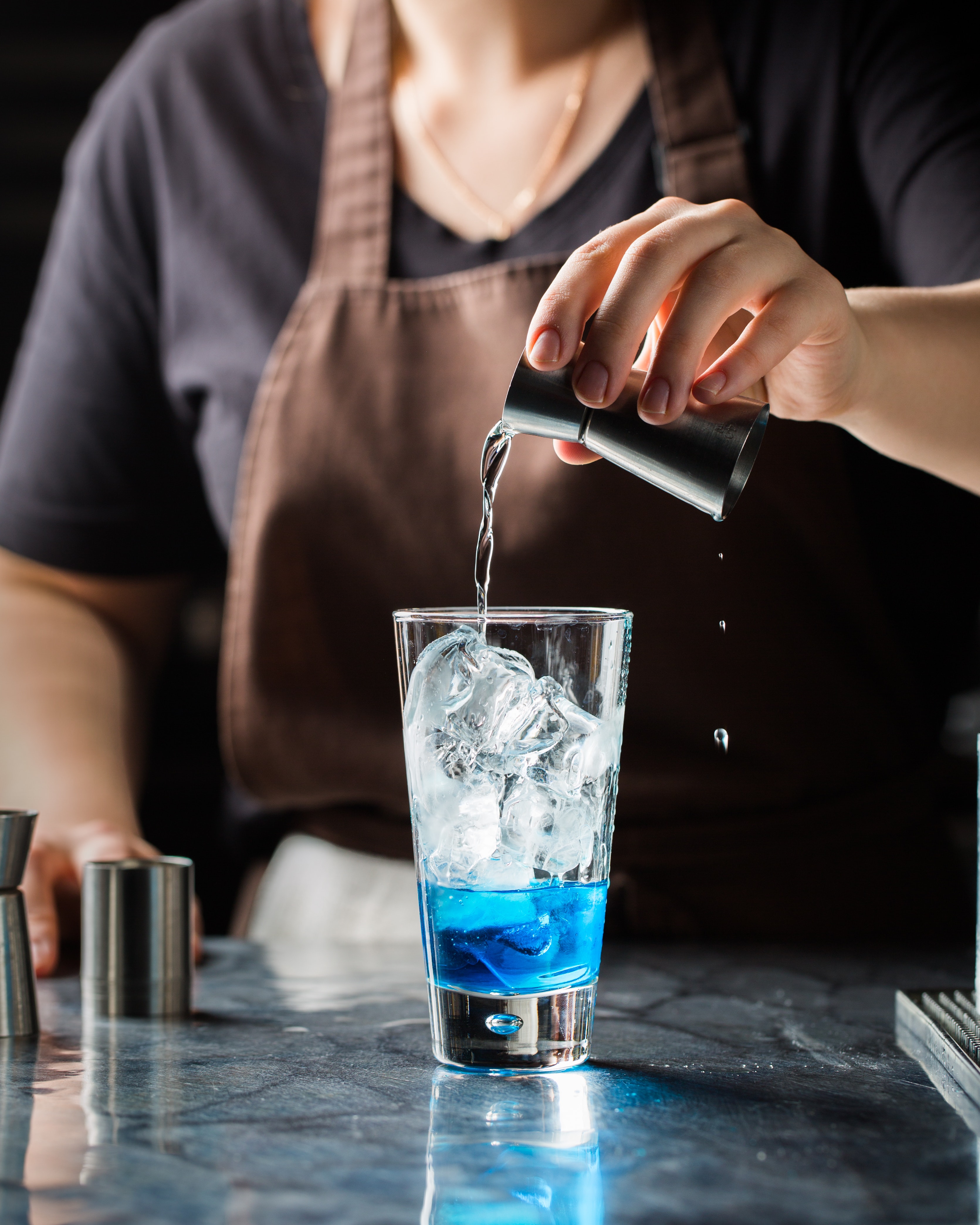 bartender pouring shot into iced filled glass