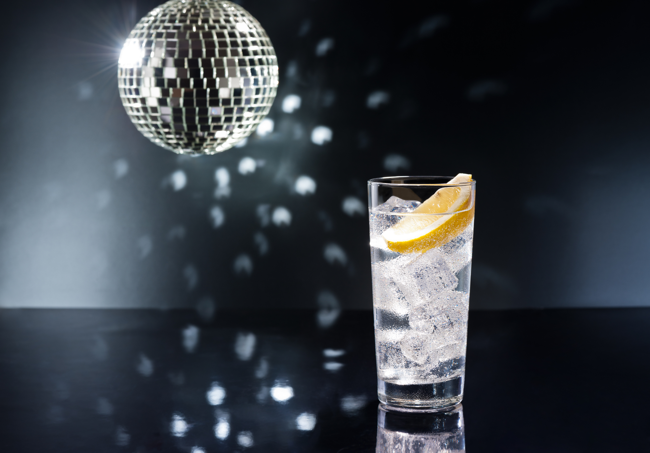 vodka and tonic with lemon wedge under disco ball